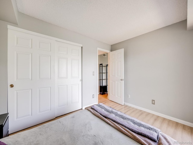 2575 S Syracuse Way Unit K201, Denver, CO 80231 - unfurnished bedroom featuring wood finished floors, baseboards, a closet, and a textured ceiling