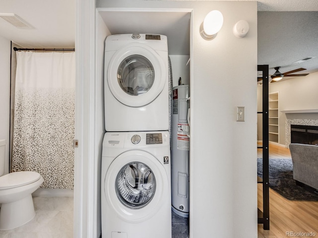 2575 S Syracuse Way Unit K201, Denver, CO 80231 - laundry room with stacked washing machine and dryer, a ceiling fan, wood finished floors, water heater, and a fireplace
