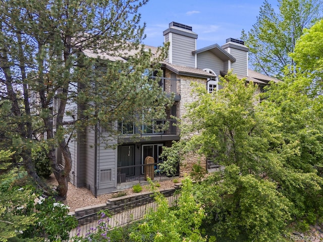 2575 S Syracuse Way Unit K201, Denver, CO 80231 - rear view of house featuring a chimney, a balcony, and stone siding