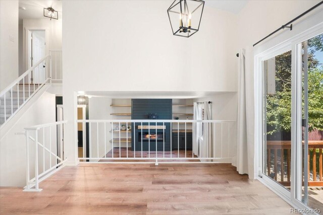 6318 Newton Ct, Arvada, CO 80003 - unfurnished living room with wood finished floors, a chandelier, stairway, and a tiled fireplace