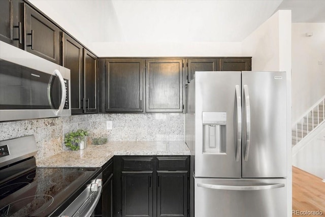 6318 Newton Ct, Arvada, CO 80003 - kitchen featuring appliances with stainless steel finishes, tasteful backsplash, light stone countertops, and dark brown cabinetry