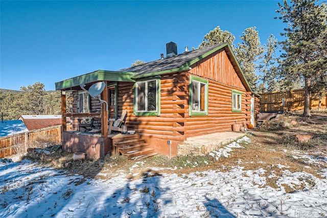 view of home's exterior featuring fence and log siding