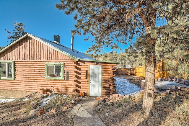 rear view of property featuring log siding and fence