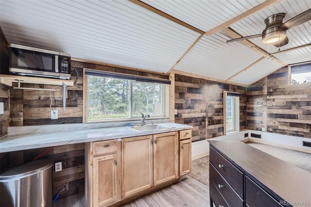 34502 Chilton Ave, Pine, CO 80470 - kitchen featuring wooden walls, stainless steel microwave, vaulted ceiling, light wood-style floors, and a sink