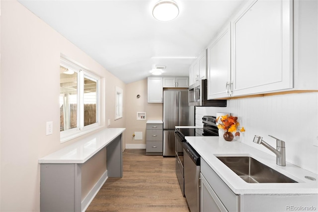 kitchen with light hardwood / wood-style floors, sink, white cabinetry, vaulted ceiling, and appliances with stainless steel finishes