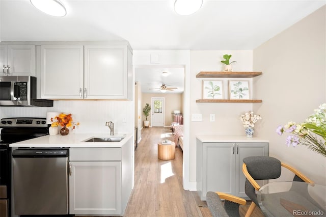 kitchen with ceiling fan, sink, stainless steel appliances, and light hardwood / wood-style floors