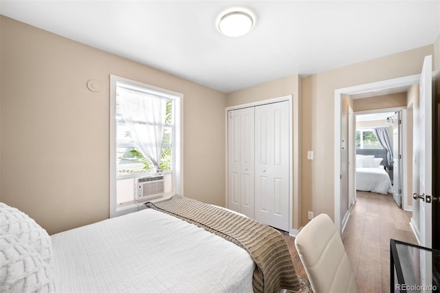 bedroom with a closet, light hardwood / wood-style floors, and cooling unit