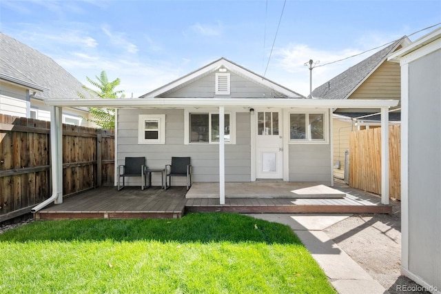 back of house with a lawn and a deck