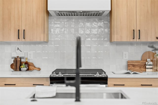 kitchen featuring decorative backsplash, light brown cabinetry, and range hood