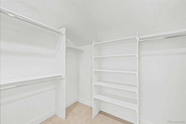 spacious closet featuring light colored carpet and vaulted ceiling