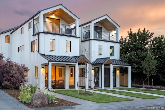 view of front of house featuring a lawn and a balcony