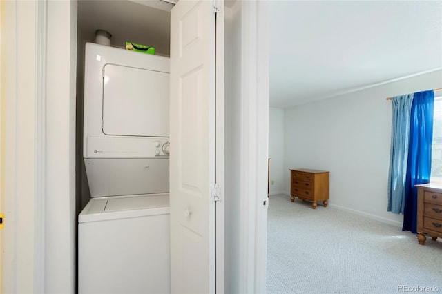 laundry room with carpet floors, baseboards, stacked washer and clothes dryer, and laundry area