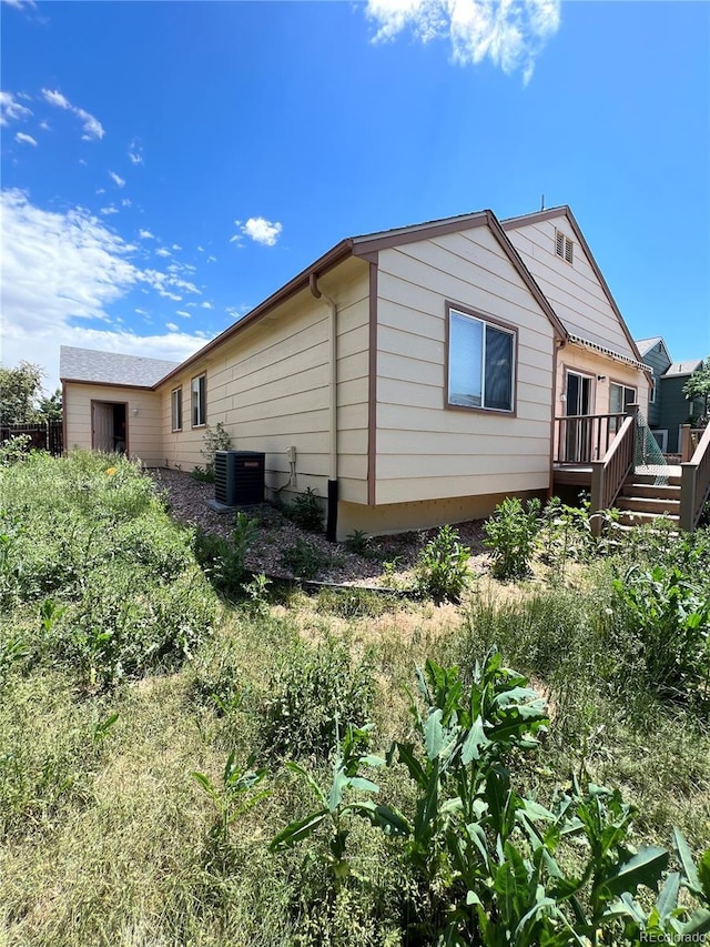 view of side of property featuring cooling unit and a wooden deck