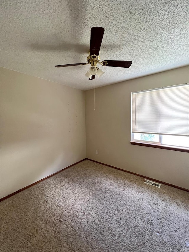 carpeted spare room with a textured ceiling and ceiling fan