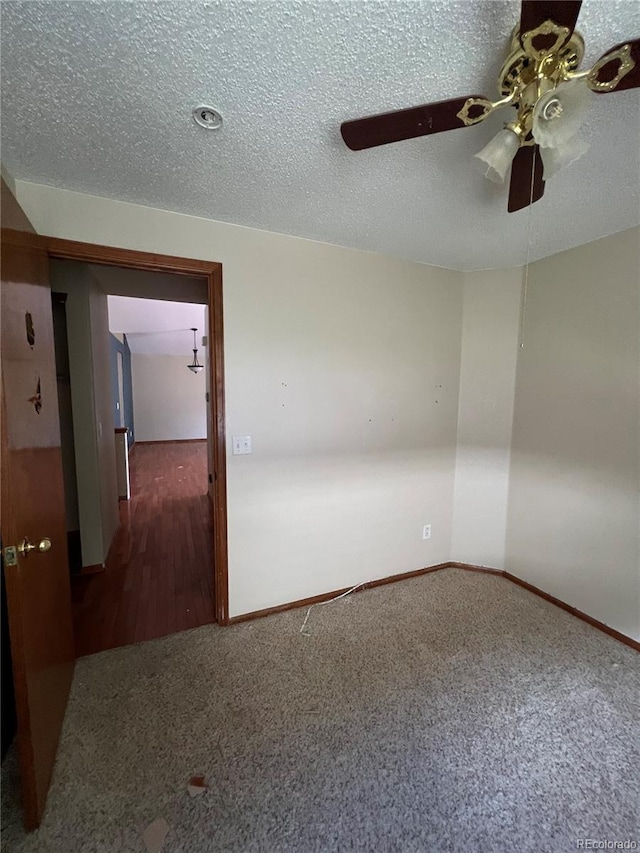 carpeted spare room featuring a textured ceiling and ceiling fan