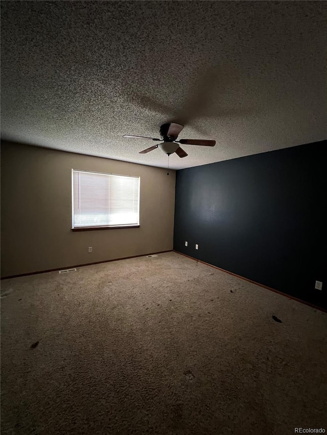 carpeted spare room with a textured ceiling and ceiling fan