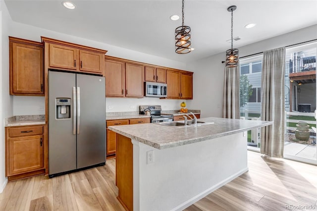 3599 Makley Cir, Castle Rock, CO 80104 - kitchen with appliances with stainless steel finishes, brown cabinetry, light wood-type flooring, light countertops, and a kitchen island with sink