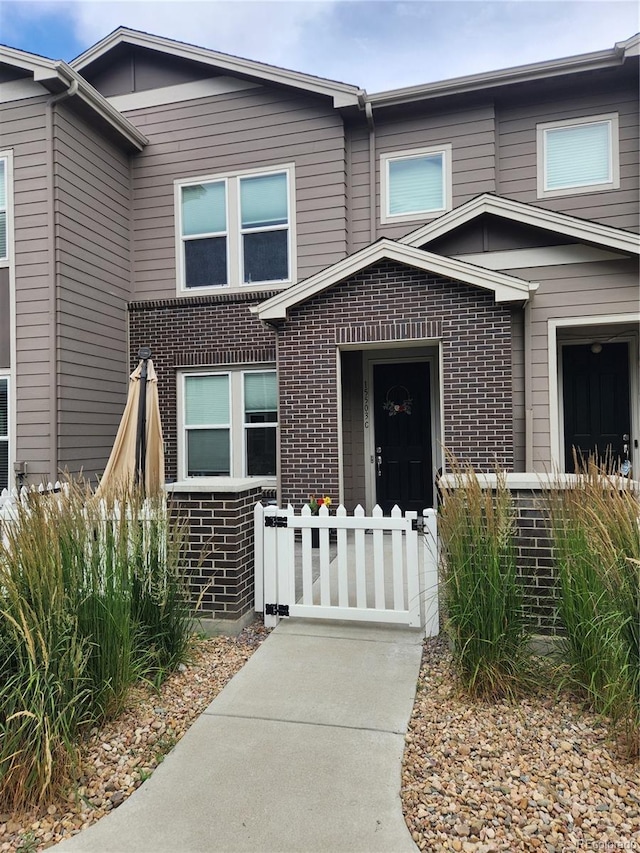 15503 W 65th Ave Unit C, Arvada, CO 80007 - view of front facade featuring brick siding, a fenced front yard, and a gate