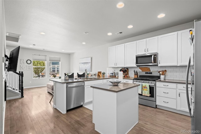 15503 W 65th Ave Unit C, Arvada, CO 80007 - kitchen featuring stainless steel appliances, dark countertops, a peninsula, tasteful backsplash, and white cabinetry