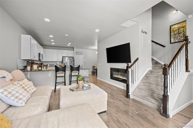 15503 W 65th Ave Unit C, Arvada, CO 80007 - living area with light wood finished floors, recessed lighting, stairway, and a glass covered fireplace