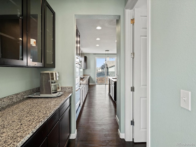 10730 Hillrose St, Parker, CO 80134 - kitchen featuring dark wood-style floors, glass insert cabinets, light stone countertops, stainless steel oven, and recessed lighting