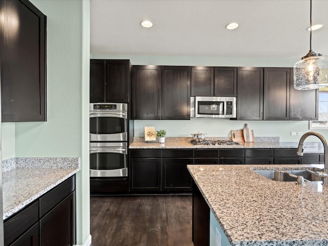 10730 Hillrose St, Parker, CO 80134 - kitchen featuring stainless steel appliances, a sink, dark wood-style floors, hanging light fixtures, and light stone countertops