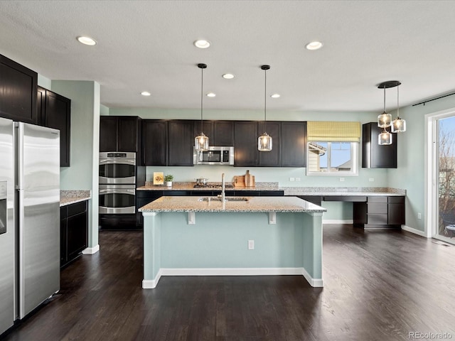 10730 Hillrose St, Parker, CO 80134 - kitchen with stainless steel appliances, a sink, dark wood finished floors, recessed lighting, and a breakfast bar