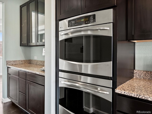 10730 Hillrose St, Parker, CO 80134 - kitchen with double oven, dark brown cabinetry, light stone countertops, and dark wood-style floors