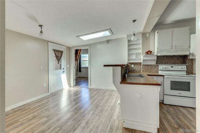 kitchen featuring hanging light fixtures, electric stove, white cabinets, a skylight, and sink