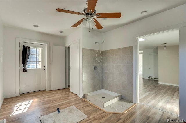 bathroom with ceiling fan, tile walls, hardwood / wood-style floors, and walk in shower