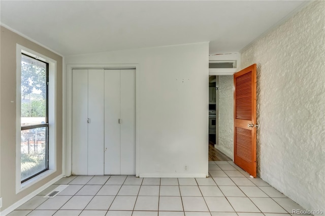 unfurnished bedroom featuring light tile patterned floors, a closet, vaulted ceiling, and multiple windows