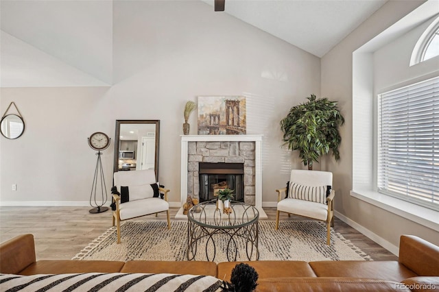 living area featuring hardwood / wood-style floors, a stone fireplace, and vaulted ceiling