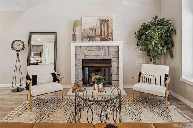 living area featuring a stone fireplace and light wood-type flooring