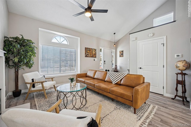 living room with ceiling fan, high vaulted ceiling, and light wood-type flooring