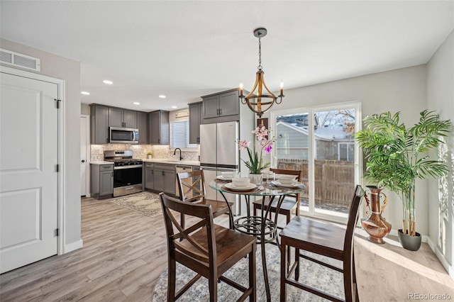 dining area featuring an inviting chandelier, sink, and light wood-type flooring