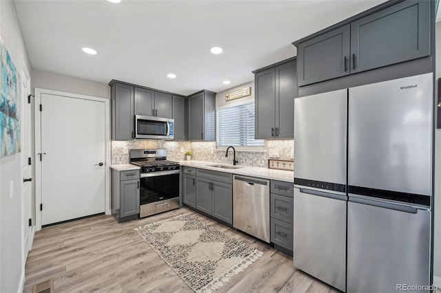 kitchen featuring stainless steel appliances, light hardwood / wood-style floors, sink, and gray cabinetry