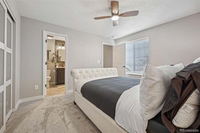 bedroom featuring light carpet, connected bathroom, a textured ceiling, and ceiling fan