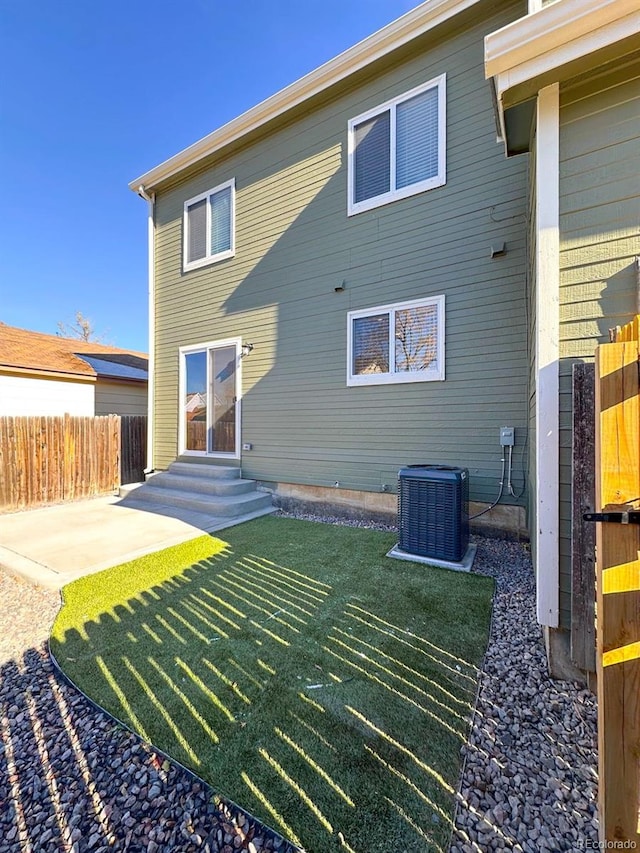 rear view of property featuring a patio area, central air condition unit, and a lawn