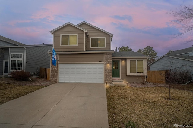 traditional home with brick siding, driveway, an attached garage, and fence