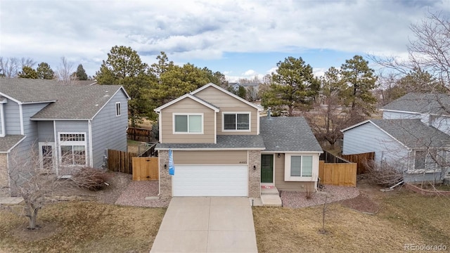 traditional home with concrete driveway, roof with shingles, an attached garage, and fence