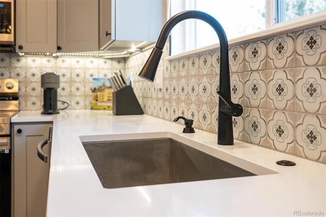 details featuring light countertops, backsplash, gray cabinetry, and stainless steel electric stove