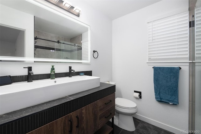 bathroom featuring a stall shower, vanity, toilet, and baseboards