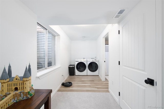 laundry room featuring carpet floors, visible vents, wood finished floors, washer and dryer, and laundry area