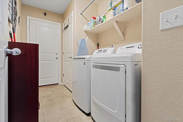 laundry room featuring laundry area, light tile patterned floors, washing machine and clothes dryer, and a textured wall