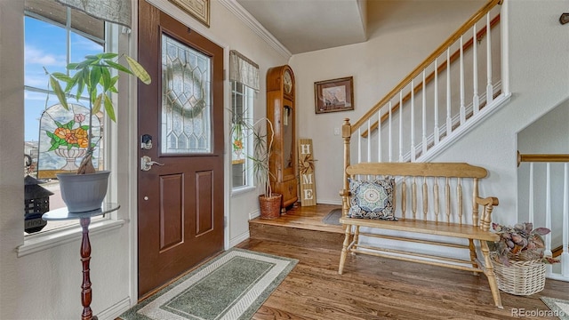 foyer entrance featuring baseboards, ornamental molding, wood finished floors, and stairway