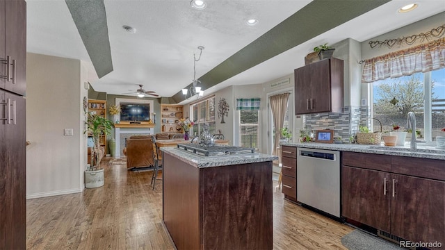 kitchen featuring appliances with stainless steel finishes, a sink, a ceiling fan, open floor plan, and a kitchen island