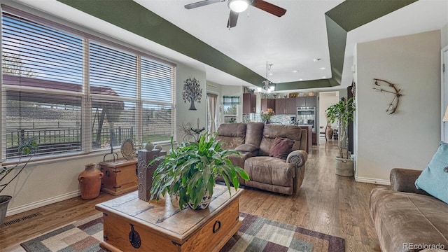 living area featuring baseboards, ceiling fan with notable chandelier, and wood finished floors