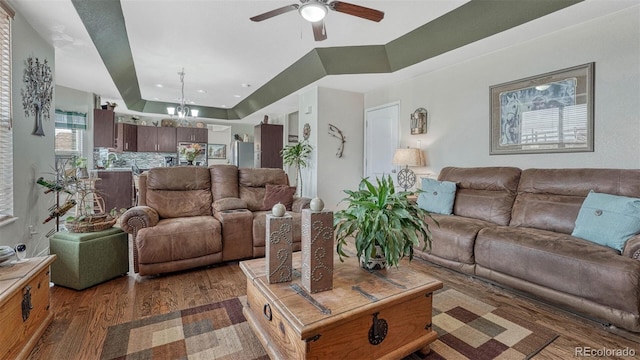 living area with a ceiling fan, recessed lighting, wood finished floors, and a raised ceiling