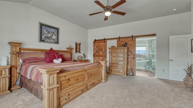 bedroom featuring ensuite bathroom, a barn door, vaulted ceiling, and light carpet