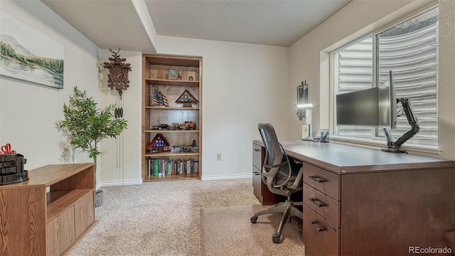 office space featuring baseboards, built in shelves, and light colored carpet